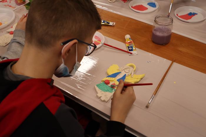 Chłopiec maluje farbami figurę anioła